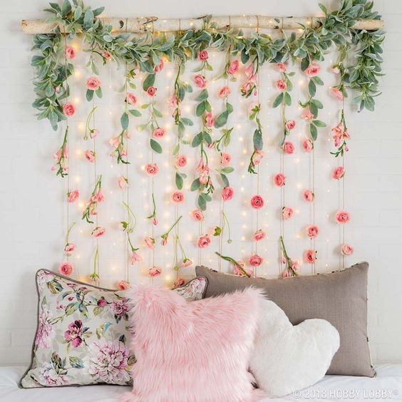 اتاق خوابی که از دیوار پشت تخت آن ریسه های گل رز صورتی رنگ آویزان شده است